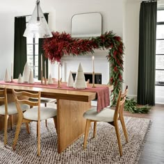 a dining room table decorated for christmas with greenery and candles