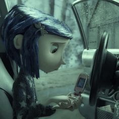 an animated doll holding a cell phone sitting in the driver's seat