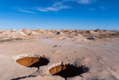 an open desert area with rocks and dirt in the foreground, under a blue sky