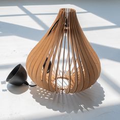 a wooden lamp sitting on top of a white floor next to a black light bulb