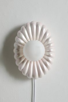 a white flower shaped object mounted on the wall