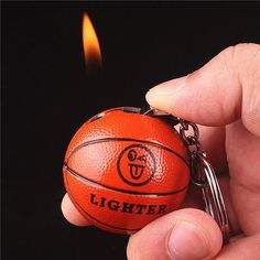 a hand holding a basketball keychain with a lighter burning in the back ground