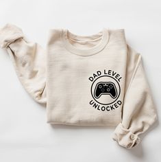 Dad Level Unlocked Sweatshirt, Gaming Dad Shirt, Funny New Dad Shirt, First Time Dad, Gamer Dad Gift, Father's Day Gift, New Father Gift       Hi! Welcome to the LaTeeApparel! It's great to see you here! Our shirts are clean, high quality and soft. It is prepared quickly by our store! Enjoy your shopping! It is a pleasure for us to help you with your questions and you can reach us at any time. F I T  ∙ S I Z I N G  -->Women's sizes are narrower than the waist -->Sleeves are rolled up in some pro Everyday Long Sleeve Shirt With Letter Print, Casual Crew Neck Tops For Father's Day, Father's Day Casual Graphic Sweatshirt, Casual Graphic Print Sweatshirt For Father's Day, Casual Cotton Tops For Father's Day, Father's Day Casual Slogan Tops, Father's Day Cotton Crew Neck Sweatshirt, Long Sleeve Top With Text Print For Father's Day, Casual Crew Neck Sweatshirt For Father's Day