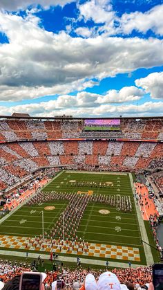 an orange and white football stadium filled with people watching the band play on the field