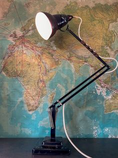 a desk lamp sitting on top of a wooden table next to a map with lines