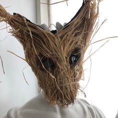 a close up of a mask made out of straw with eyes and hair on it