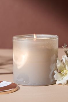 a white candle sitting on top of a table next to a phone