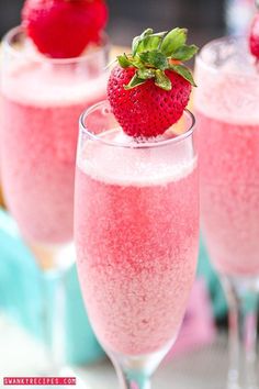 two glasses filled with pink liquid and a strawberry on the top one has a green leaf