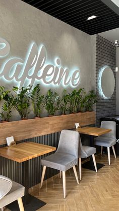 the interior of a restaurant with wooden tables and grey chairs, plants on the wall