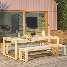 a table and bench on a wooden deck with sliding glass doors to the outside patio