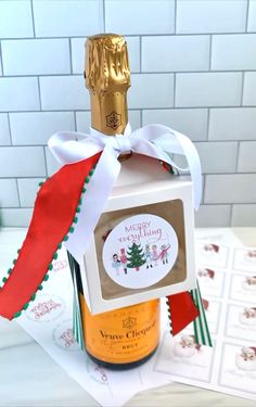 a bottle of wine with a red ribbon around it on top of a table next to some cards