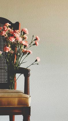 a chair with flowers in it sitting against a wall