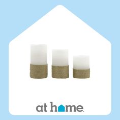 three white candles sitting in front of a blue background with the words at home on it