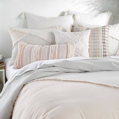 a bed with white sheets and pillows on top of it