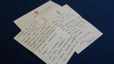 three pieces of paper with writing on them sitting on a blue tablecloth covered surface