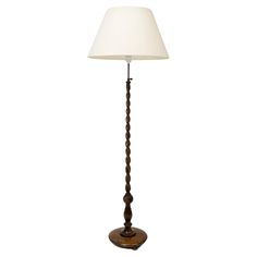 a wooden floor lamp with a white shade