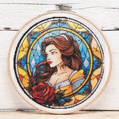 a cross stitch pattern with a beautiful woman holding a rose in her right hand, on a white wooden background