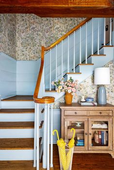 a yellow umbrella sitting on top of a wooden floor next to a stair case and table