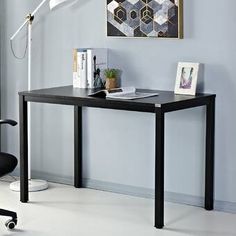 a black desk with a lamp and pictures on the wall above it, along with an office chair