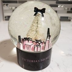 a snow globe with a christmas tree in it on top of a marble countertop