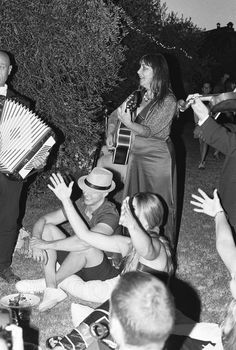 a group of people sitting around each other on the grass with an accordion in front of them