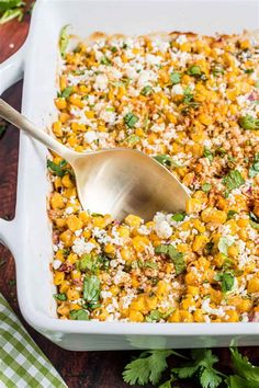 a white casserole dish filled with corn and rice topped with cilantro