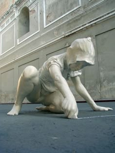 a white statue laying on its side in front of a building