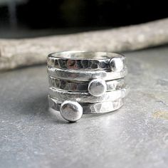 Set of FIVE stacking rings. Rustic stacking pebble rings accented by two textured fine silver bands. The 3 stackable sterling silver pebbles have been given an oxidized finish that is a great contrast to the two satin textured bright white fine silver accent rings. Meant to be slightly organic in shape, this rustic stack is a great casual, everyday look. They are also fun to play with, changing the position of the pebbles according to mood. when stacked on top of each other, they remind me of th Unique Hammered Stackable Rings For Promise, Hammered Silver Stackable Promise Rings, Silver Hammered Stackable Promise Rings, Stacked Sterling Silver Rings, Unique Hammered Silver Stackable Rings, Unique Hammered Stackable Rings For Anniversary, Adjustable Stacked Silver Rings, Unique Silver Stackable Rings With Hammered Detail, Stacked Sterling Silver Rings In Silver