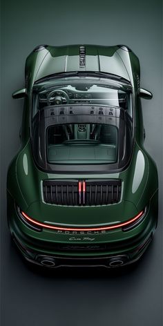 the rear view of a green sports car with its hood open and lights on, from above