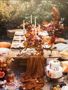 the table is set with candles, plates and flowers on it for an autumn celebration