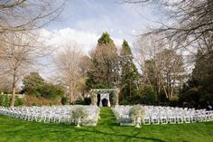 an outdoor ceremony set up with white chairs