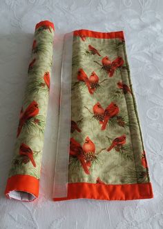 two pieces of fabric with red birds on them sitting on a white tableclothed surface