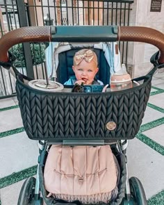 a baby sitting in a stroller on the sidewalk