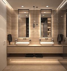 a bathroom with two sinks, mirrors and lights on the wall above them is illuminated by recessed lighting