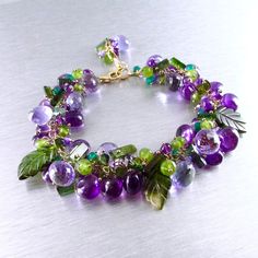 "When I started making this very chunky bracelet, I had no idea in mind. I just started grabbing some new beautiful amethyst briolettes that I had just gotten that day and pairing them with nice dark green tourmaline carved leaves. I've had Spring in mind, so fresh green sprigs of green vesuvianite are popping up all over the bracelet. New fresh flower buds, represented by the lavender faceted onion cut quartz, peek out from behind the carved tourmaline leaves.. New Easter bulbs are braking the Beaded Gemstone Jewelry, Chunky Beaded Bracelets, Gemstone Combinations, Cluster Bracelet, Colorful Bracelet, Cluster Bracelets, Viral Reels, Vintage Jewelry Repurposed, Chunky Bracelet