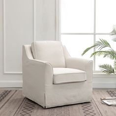 a white chair sitting in front of a window next to a potted palm tree