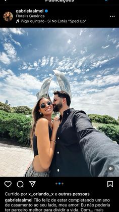 a man and woman taking a selfie in front of a blue sky with clouds