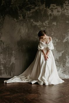 a woman in a white dress is sitting on the floor with her back to the camera