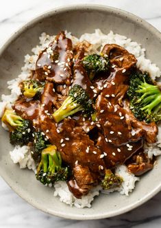 a bowl filled with beef and broccoli covered in sauce on top of rice