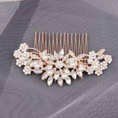 a bridal hair comb with pearls and crystal stones on the headpiece is laying on a piece of fabric