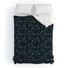 a bed with white pillows and black floral comforter set on it's side