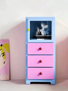 a pink and blue dresser sitting next to a box with a toy horse on it