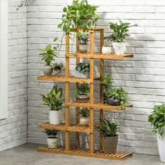 a wooden shelf filled with potted plants next to a brick wall