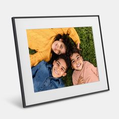 three children laying down in the grass with their arms around each other and smiling at the camera