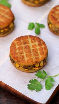 mini waffle sandwiches with corn and cheese are on a cutting board next to parsley