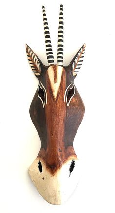 an animal mask with long horns and feathers on it's head is mounted to the wall