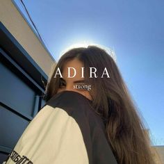 a woman with long brown hair standing in front of a blue building and the words adria strong