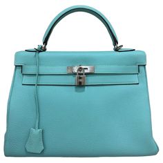 Borsa firmata Hermès, modello Kelly, misura 32, realizzata in pelle Clemence, morbida al tatto con grana grossa, nella colorazione Blue Atoll. Dotata di una patta con chiusura ad incastro con fascia orizzontale, lucchetto e clochette con chiavi. Munita di un manico centrale per portata a mano e di una tracolla rimovibile per indossare la borsa a spalla. Caratterizzata da hardware argento, internamente rivestita in pelle tono su tono, molto capiente con presenza di tasche con e senza zip. Anno di produzione 2014, si presenta in ottime condizioni. Hermès handbag, Kelly model, size 32, made of Clemence leather, soft to the touch with a coarse grain, in the Blue Atoll color. Equipped with a flap with interlocking closure with horizontal band, padlock and clochette with keys. Equipped with a ce Kelly 32, Handle Bag, Bags Shoes, Fashion Handbags, Top Handle, Top Handle Bag, Chanel, Purses And Bags, Handbags