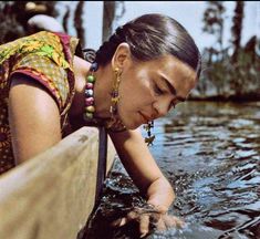 a woman in the water looking down at her hand on top of a surfboard