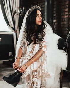 a woman in a wedding dress sitting on a chair with her veil over her head